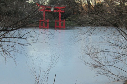 A view of the torii across an ice-covered pond in winter.