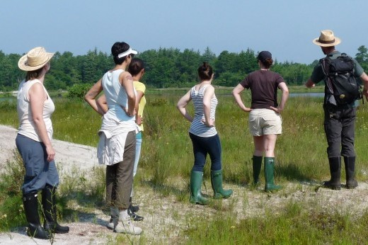 six people in a grassy area looking away from the camera